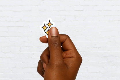 Hand holding a sticker with 3 yellow stars against a white brick wall background