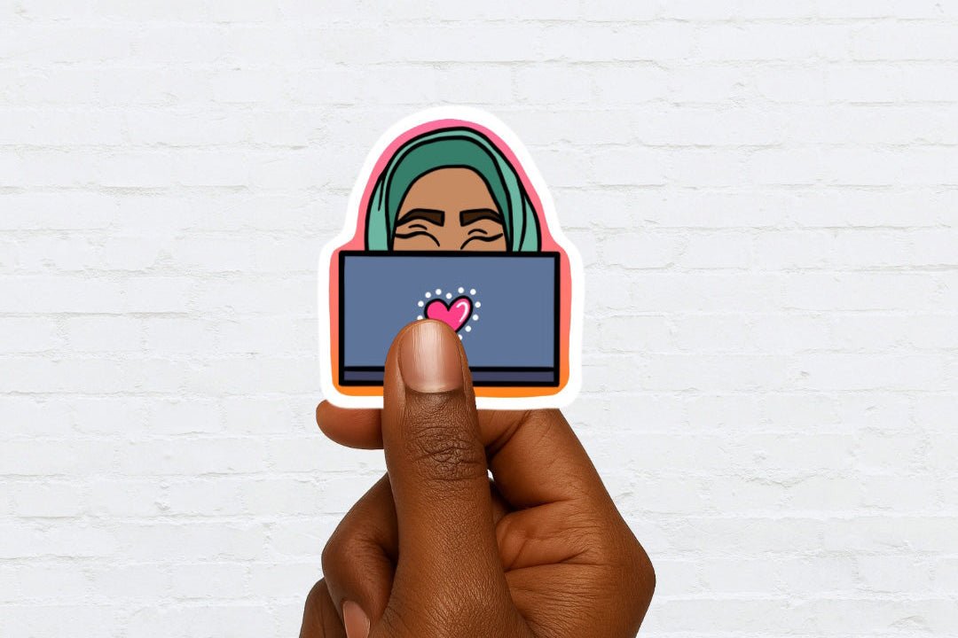 Hand holding a sticker of a woman behind a computer screen on a white brick wall background