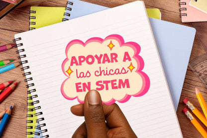 Notebook with a colorful sticker reading 'Apoyar a las chicas en STEM' on a desk with pencils.