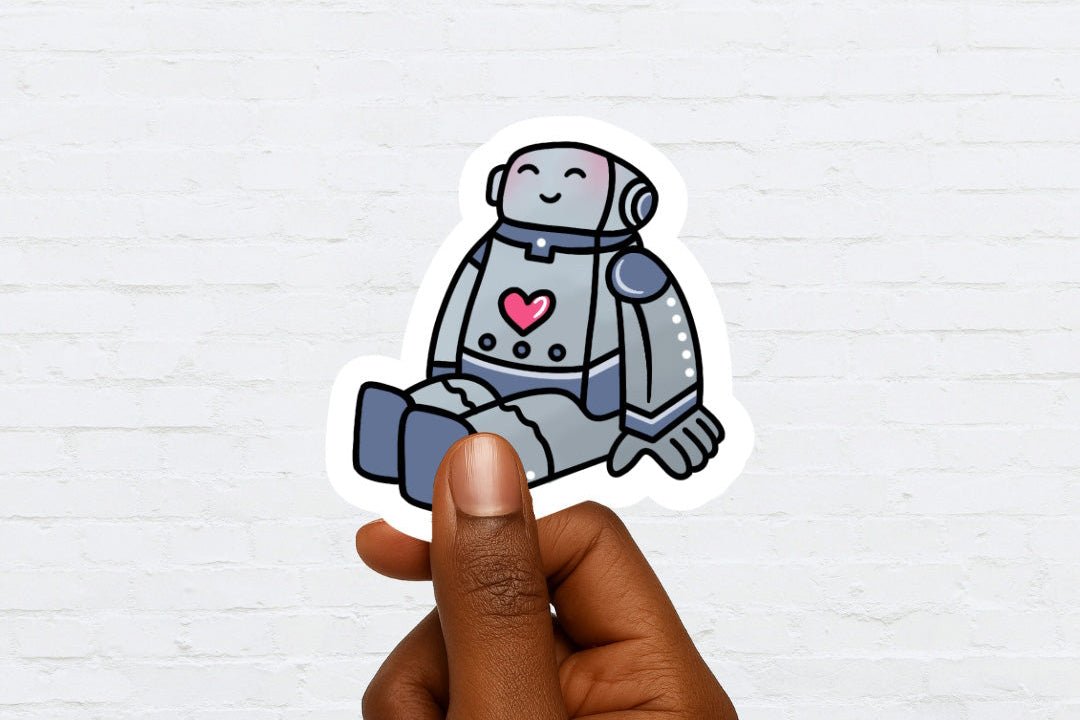 Sticker of a robot with a heart held by a hand against a white brick wall background