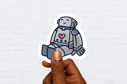 Sticker of a robot with a heart held by a hand against a white brick wall background
