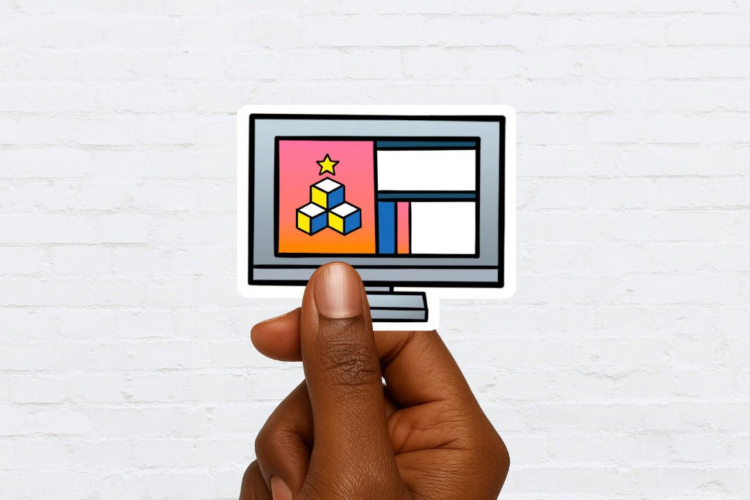 Hand holding a sticker of a computer monitor with colorful graphics on a white brick wall background